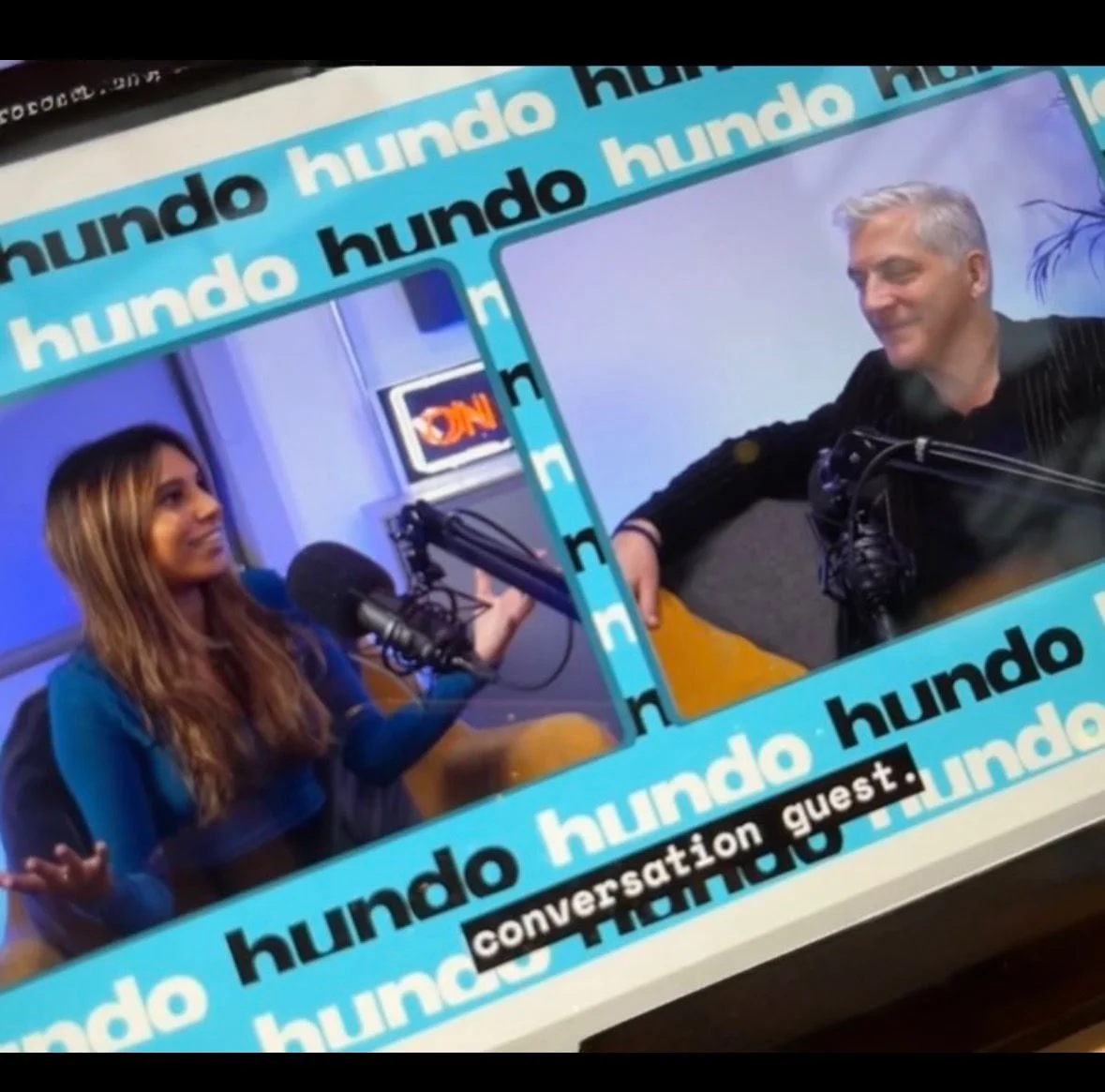 Two people in a podcast interview, each at a studio microphone
